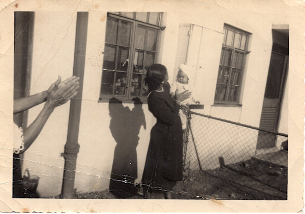 Woman holding baby, clapping hands on left by Unknown