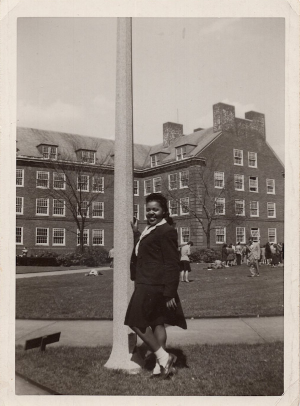 Co-ed standing at pole by Unknown