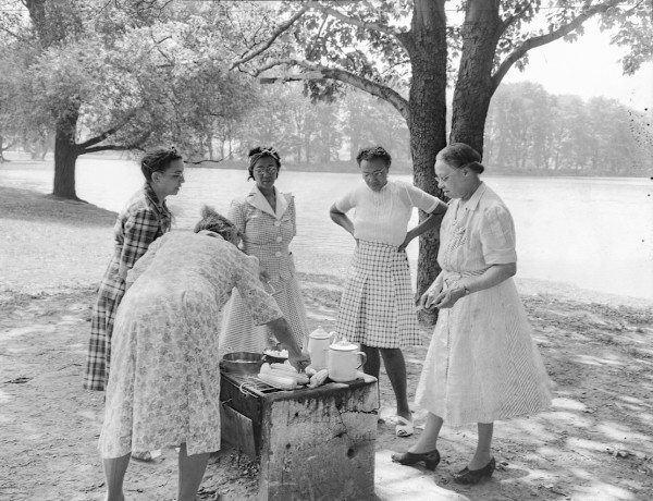 Women cooking at picnic in the park by Unknown