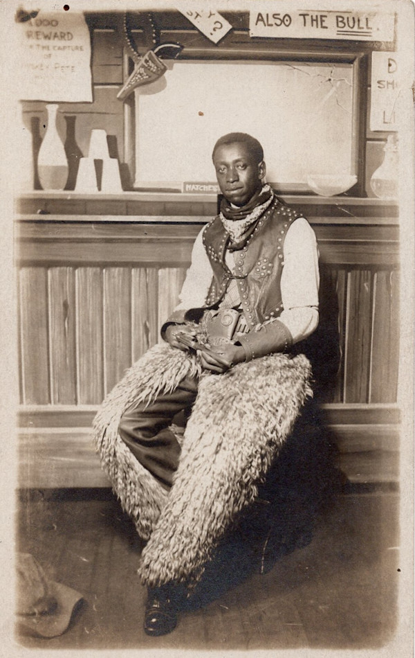 Arcade photo of man in chaps holding pistol by Unknown