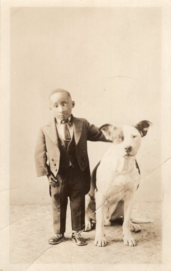 Cross-eyed boy with dog by Unknown