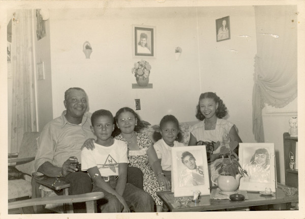 Family gathered with large photos by Unknown