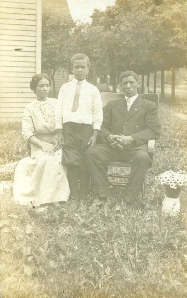 Family seated outside with vase of flowers by Unknown