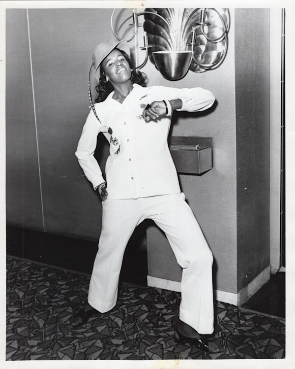 Woman posing near elevator in hat with feather by Unknown