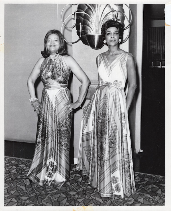 Two women modeling dresses by Unknown