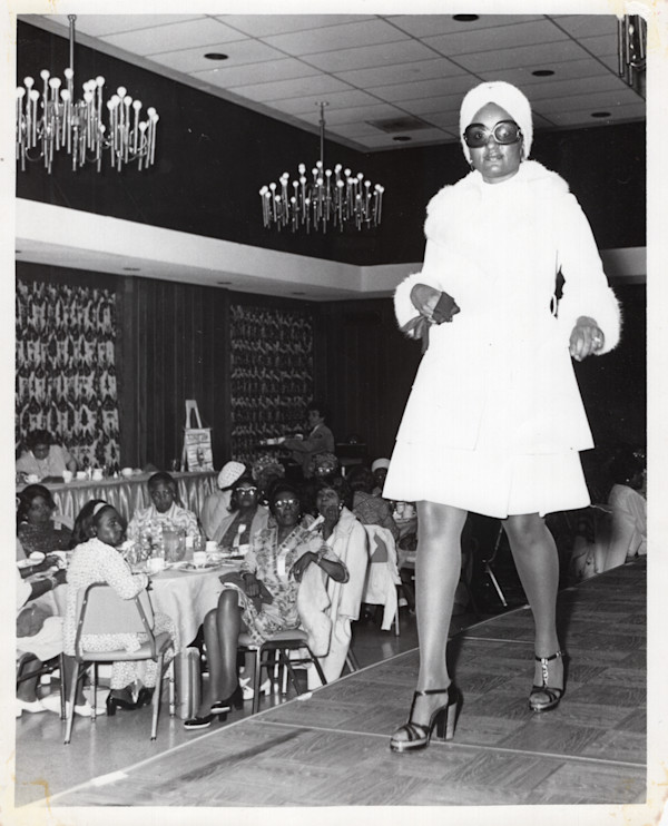 Woman walking runway in turban and sunglasses by Unknown