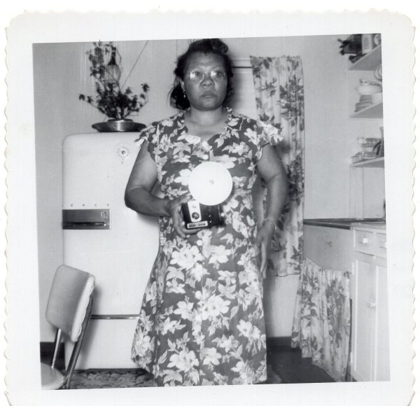 Woman in kitchen with flash camera by Unknown