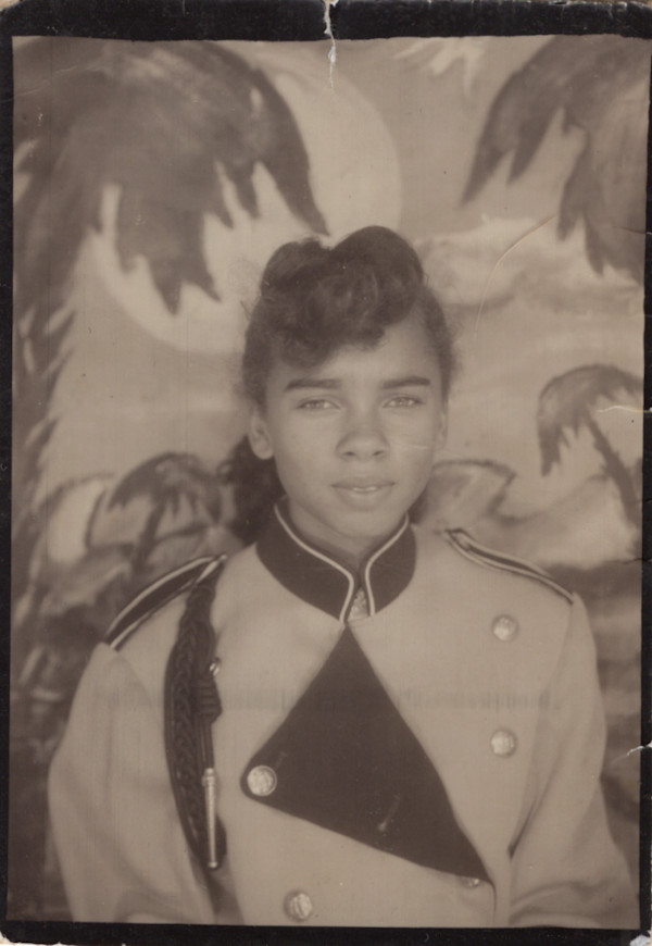 Girl in military-style uniform jacket with tropical backdrop by Unknown