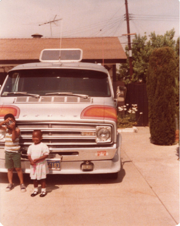 Girl & boy with camera in front of van by Unknown