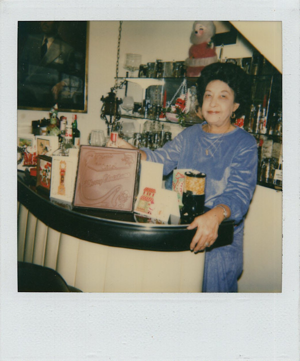 Woman tending home bar with Christmas cards displayed by Unknown