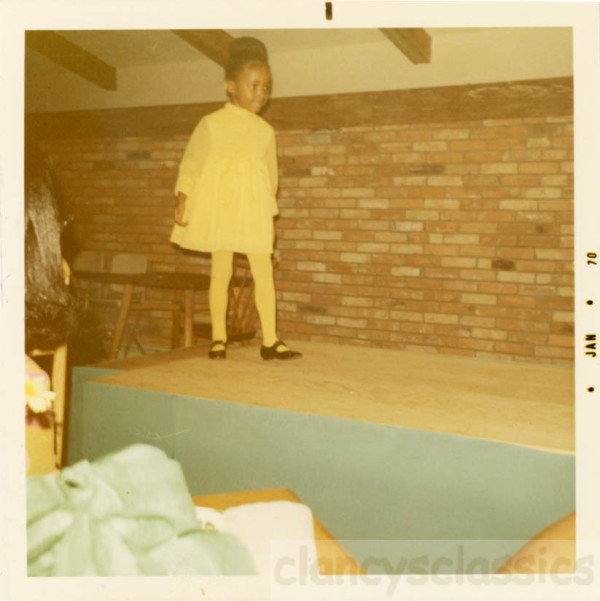 Little girl in yellow dress modeling in fashion show by Unknown
