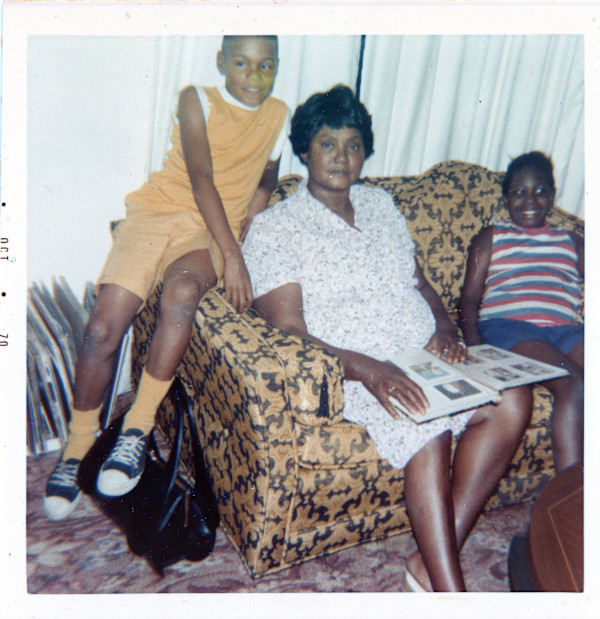 Woman with two children looking at photo album by Unknown