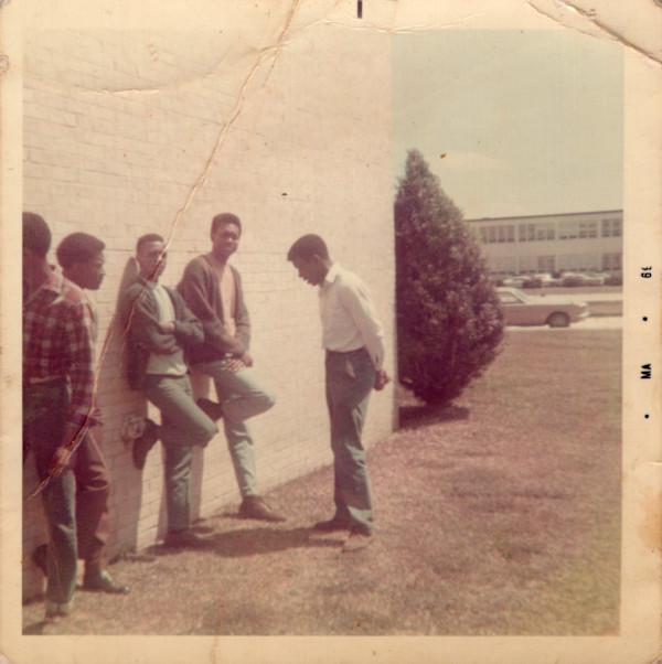 Group of men standing against building by Unknown