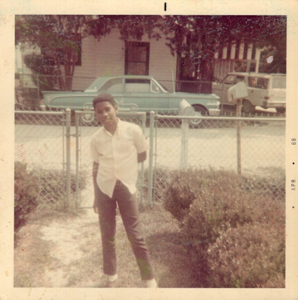 Boy standing in front yard by Unknown