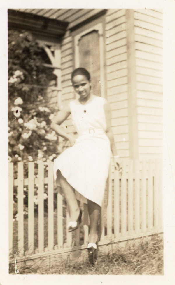 Woman posing on picket fence by Unknown