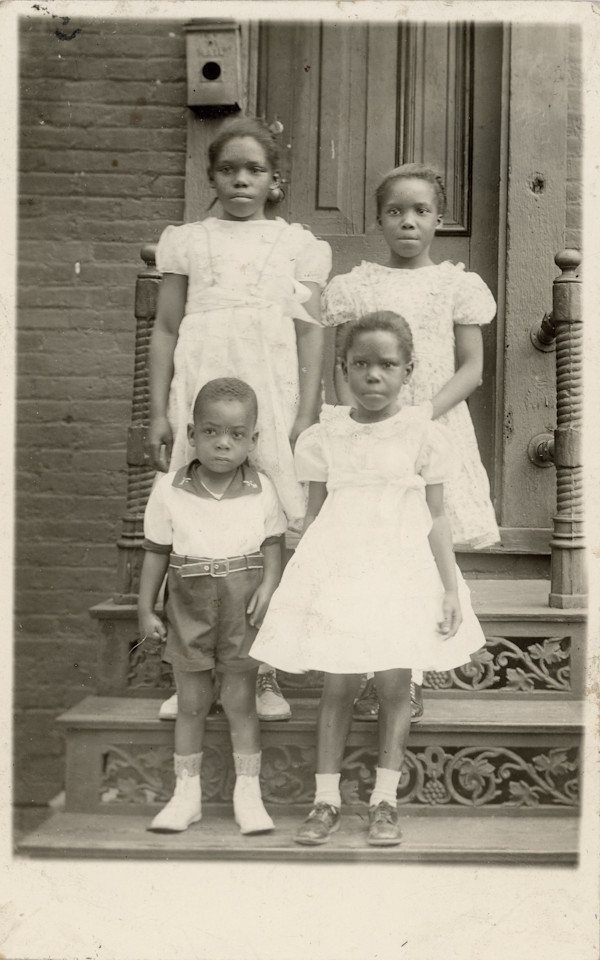 Four children posed on stoop by Unknown