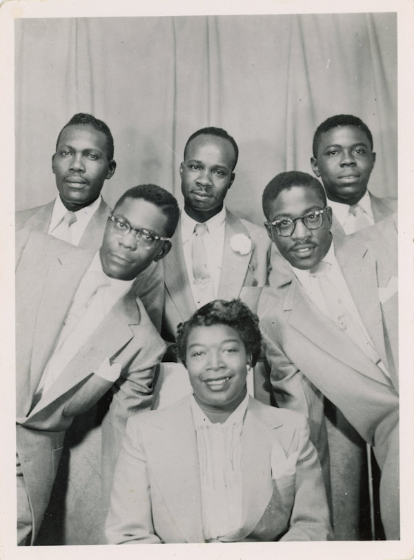 Woman flanked by five men by Unknown