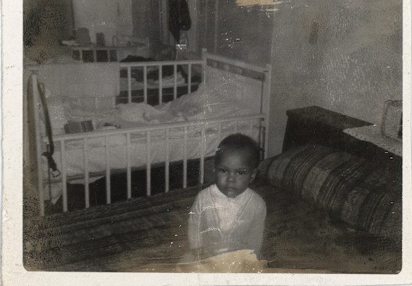 Child standing near crib by Unknown