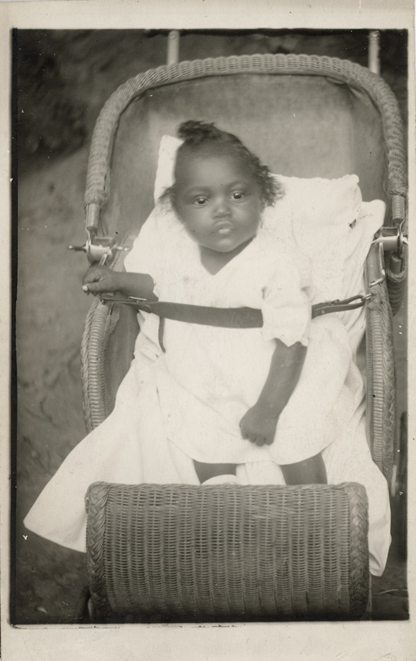 Toddler in wicker carriage by Unknown