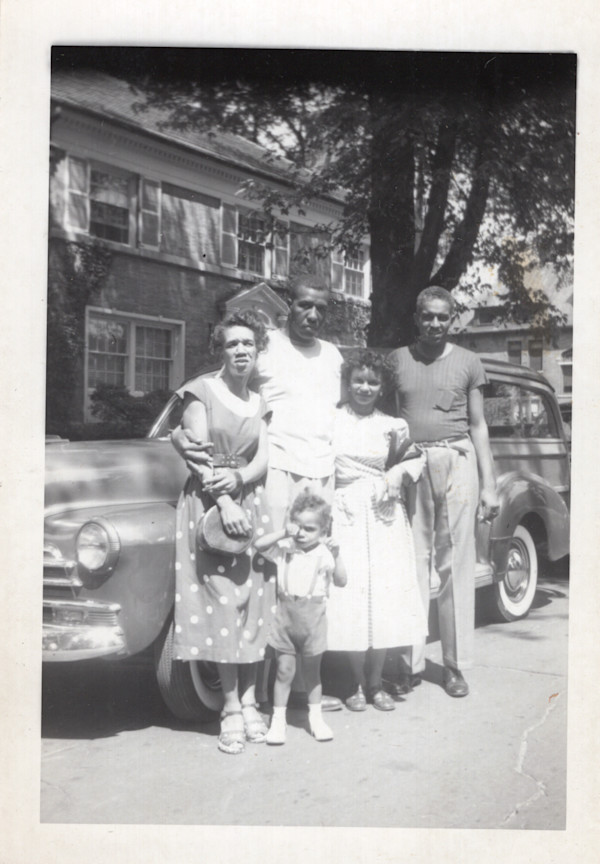 Group standing next to automobile by Unknown