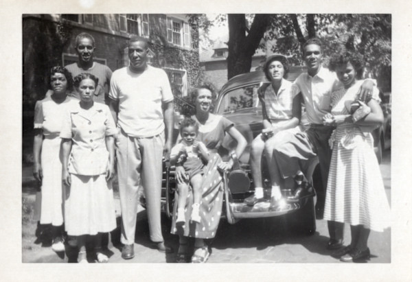 Group posing in front of automobile by Unknown