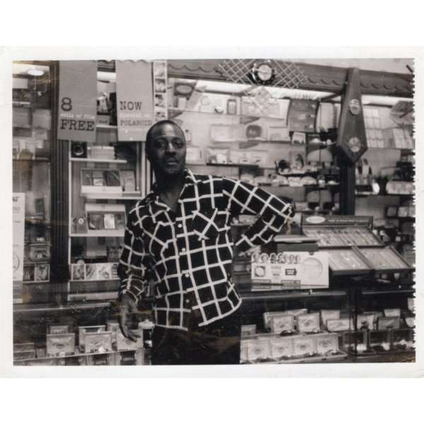 Man leaning at camera counter by Unknown