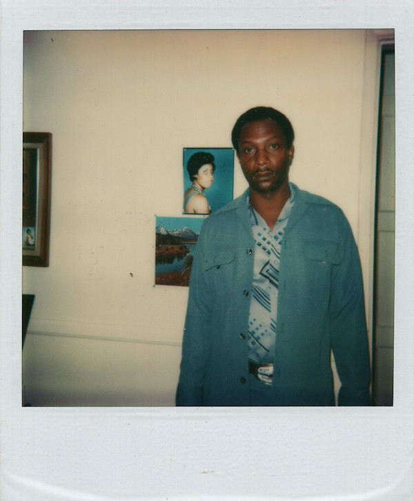 Man standing in front of wall with photos by Unknown