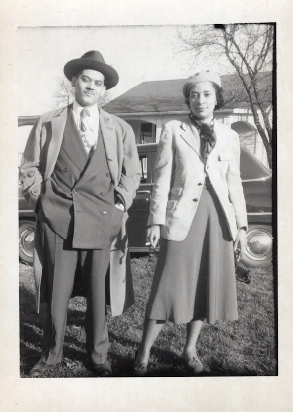 Defiant couple near automobile; woman holding cigarette by Unknown