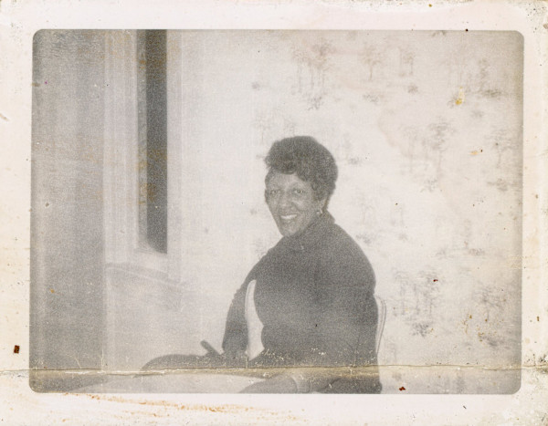 Woman in front of pale wallpaper by Unknown
