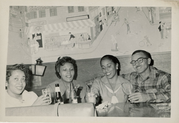 Foursome at restaurant with mural by Unknown