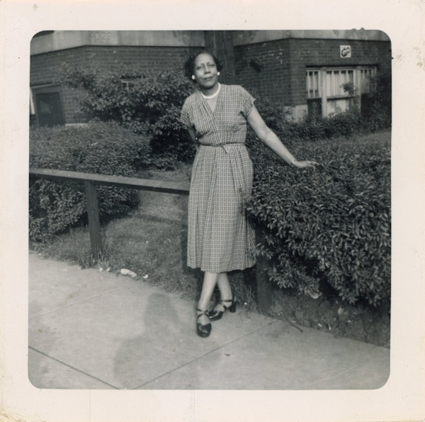 Elegant woman leaning on fence rail by Unknown