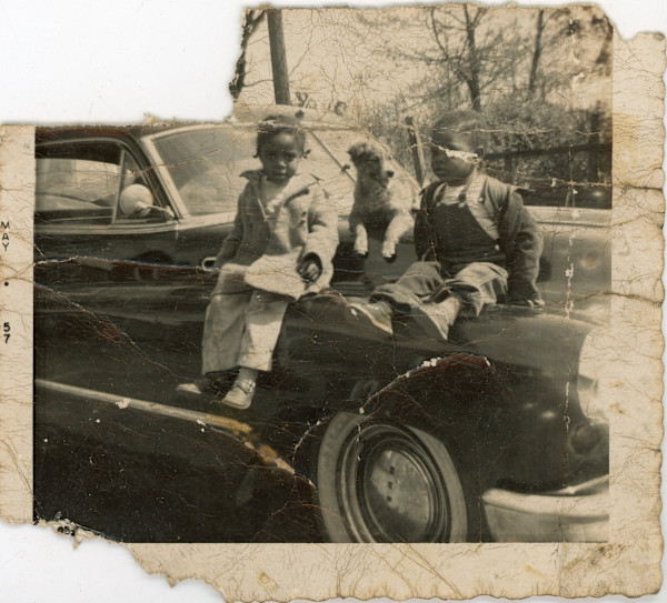 Children and dog on hood of car by Unknown
