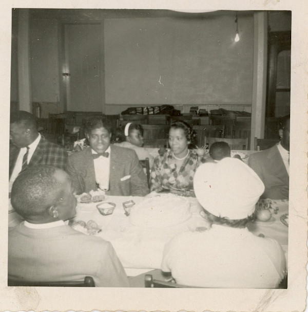 Group at dining table by Unknown
