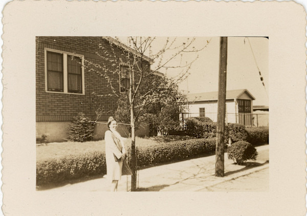 Woman standing next to young tree by Unknown