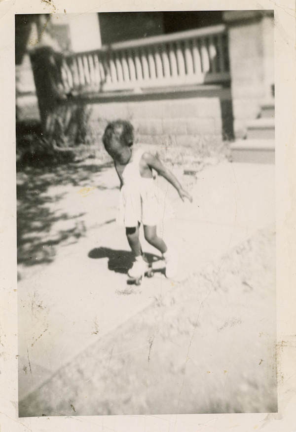 Toddler rollerskating by Unknown