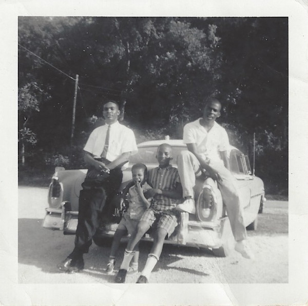 Young men and boys lounging against automobile by Unknown