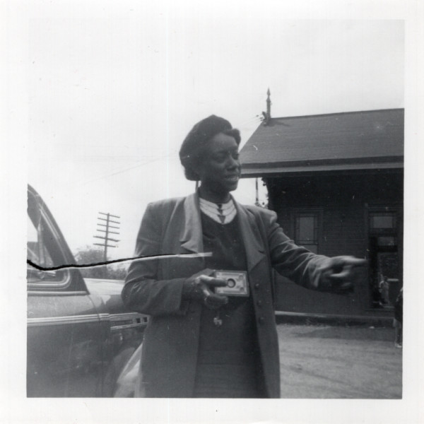 Woman holding camera and pointing by Unknown
