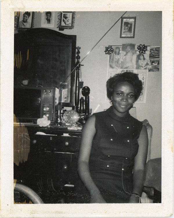 Woman in bedroom with pinups on wall by Unknown