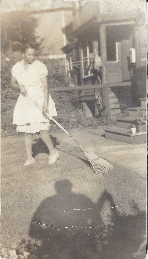 Woman raking lawn with photographer’s shadow by Unknown