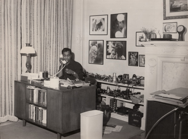 Sammy Davis, Jr. at his desk on the phone by Unknown