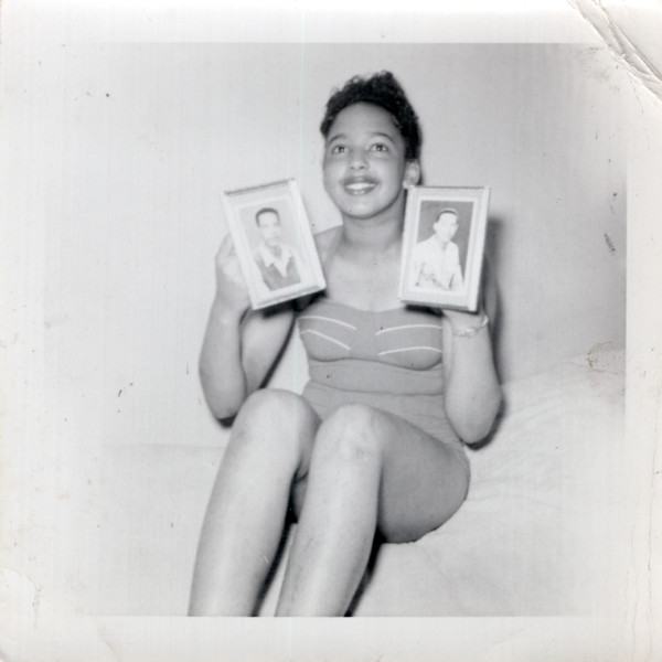 Woman holding two photos of men by Unknown