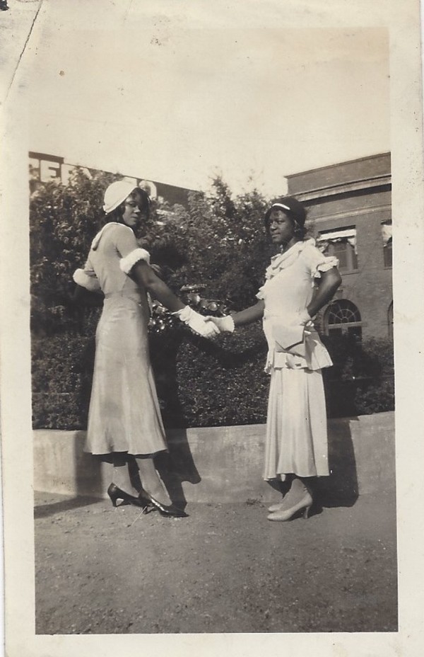 Two well-dressed young women shaking hands by Unknown