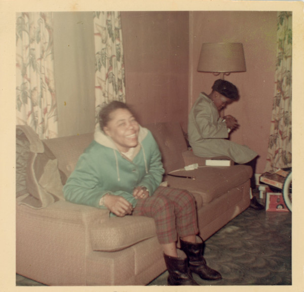 Smiling woman on sofa in pink room by Unknown