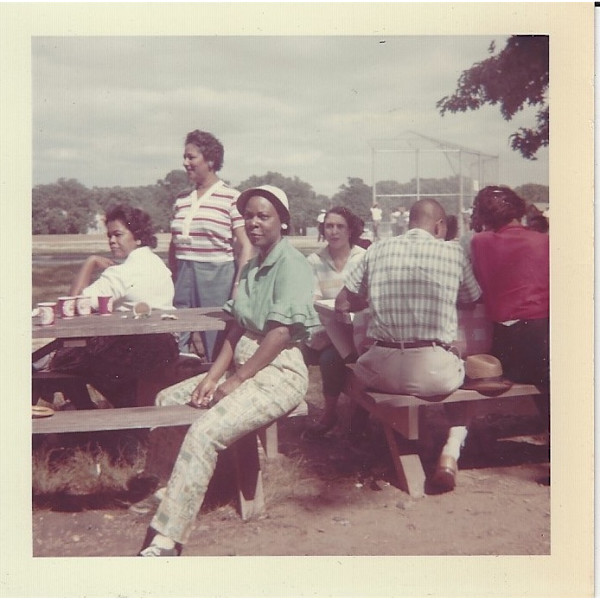 Woman straddling picnic bench by Unknown