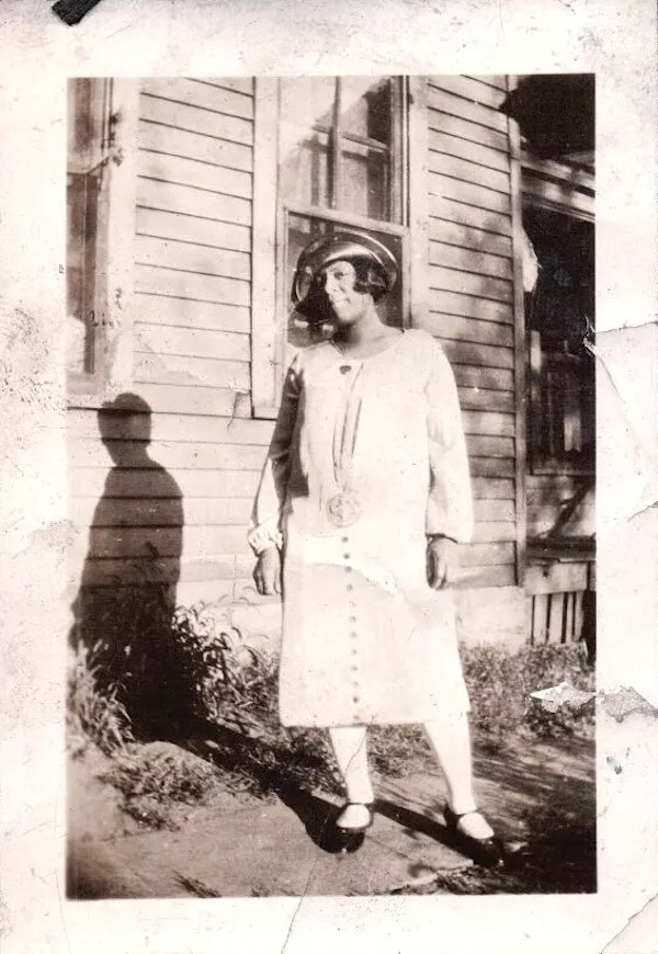 Stylish woman standing next to house by Unknown