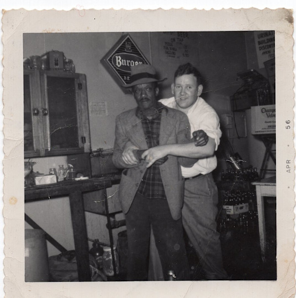 Black man embraced from behind by white man by Unknown