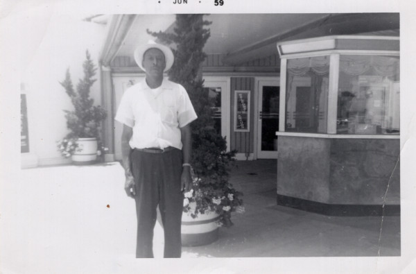 Man standing outside of theater box office by Unknown
