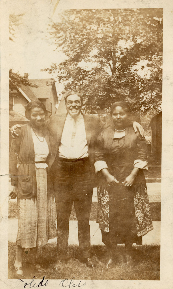 Toledo, Ohio (man making a face between two women) by Unknown