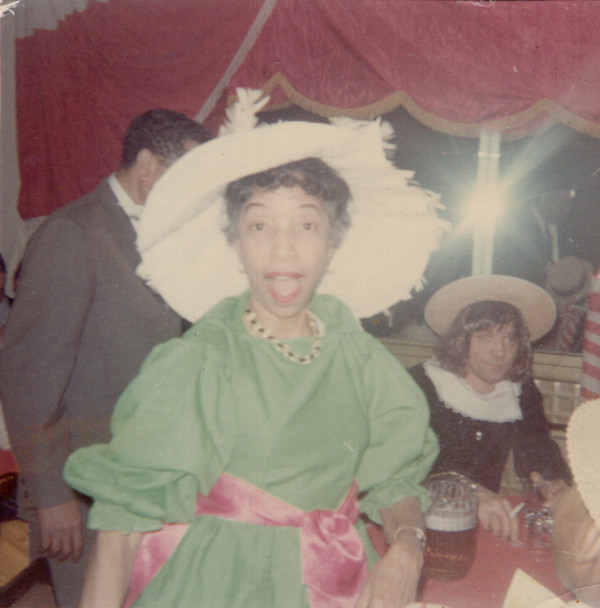 Woman in white hat and green dress at costume party by Unknown