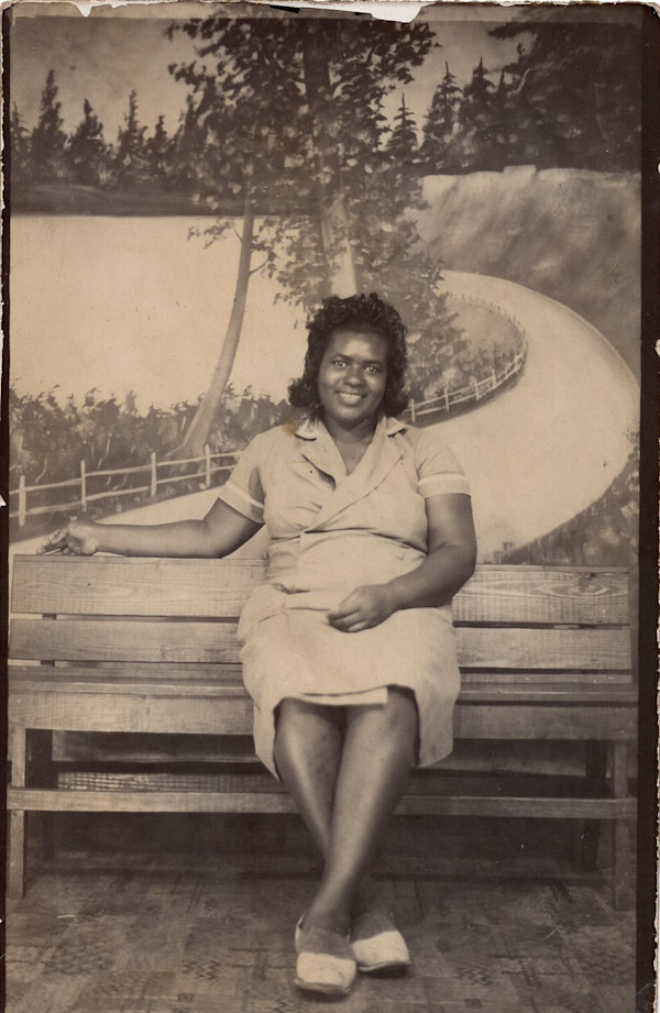 Woman seated on bench with winding road backdrop by Unknown